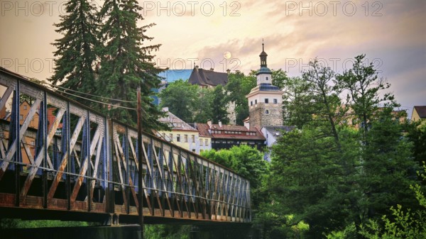 Scenic city view with bridge, historic buildings and trees at dusk, Loket, Czech Republic