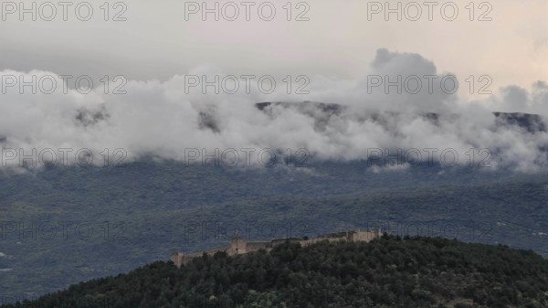 A castle is high up in the wooded mountains surrounded by clouds, North Macedonia