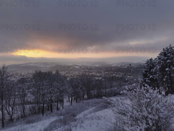 Snowy landscape with view of a village at sunset, view over Kronach in the Franconian Forest
