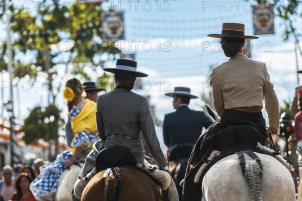 Seville, Spain, Europe. Young women and men in traditional equestrian clothes on horseback during