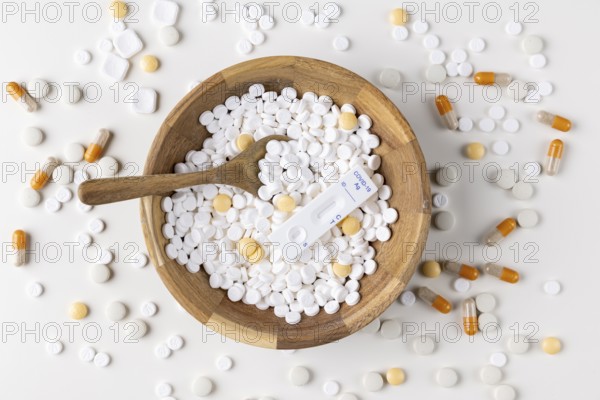Wooden bowl with tablets and a COVID test on a table