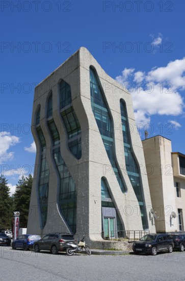 Modern, futuristic building with wavy glass facades and cars in front of it, police station