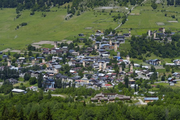 A village with scattered old houses in a green mountain landscape, defensive towers, Mestia,