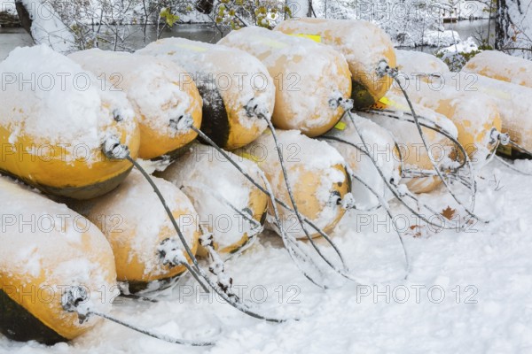 Close-up of stacked yellow cautionary river navigation buoys in storage and covered with winter