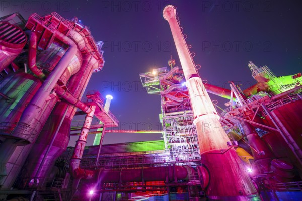 Colour-illuminated industrial ruins at night with pipes and futuristic character, Landschaftspark