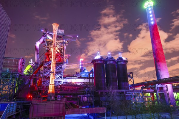 Colourful lighting on industrial buildings with visible chimney, Landschaftspark Duisburg Nord,