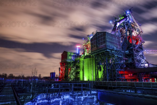 Industrial complex at dusk with colorful lighting and moving cloudy sky, Duisburg Nord Landscape