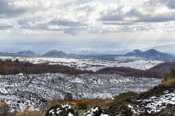 View from Silvestri Crater of dark hills with remnants of snow, barren volcanic landscape,