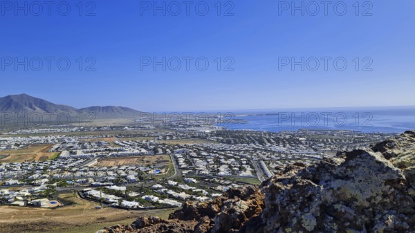 Panorama of the coastal town (Playa Blanca) with sea view and mountains under a clear sky, Playa