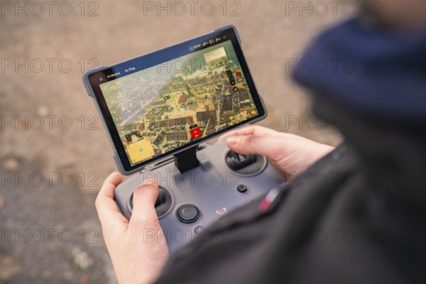 A person holds a remote control with screen for drone control, fiber optic groundbreaking,