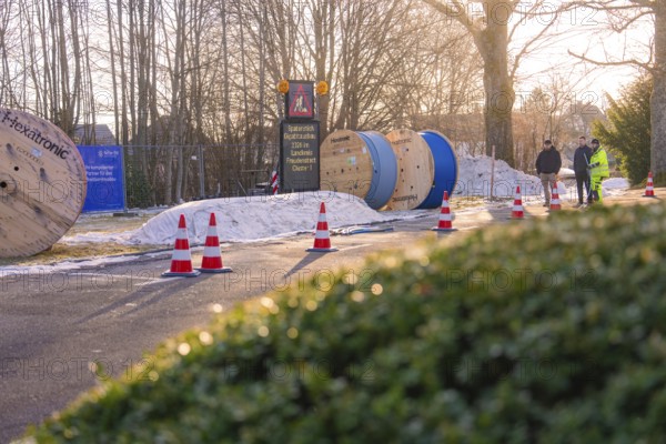 Cable rolls and traffic cones on a road in a sunny winter landscape, fiberglass groundbreaking,