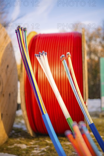 Colourful cables in front of large, red cable spools in a winter environment, fibre-optic
