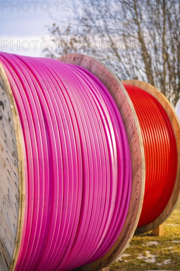 Large, coloured cable drums with pink and red cables outdoors, fibreglass groundbreaking,