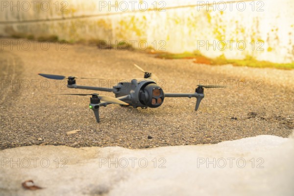 A black drone is lying on an asphalt path for outdoor use, fiberglass groundbreaking, Freudenstadt,