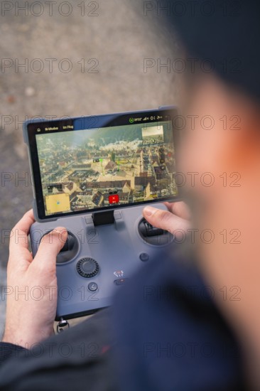 Person controls a drone with a remote control whose screen shows a city, fiberglass groundbreaking,