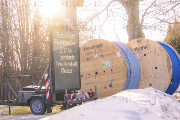 Two rolls of cable next to a glowing construction site sign in a winter environment, fibreglass