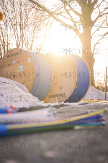 Cable rolls in sunset with snowy ground and bare trees in the background, fiberglass