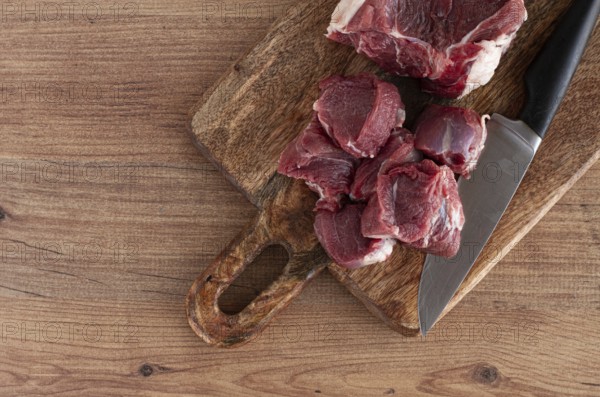 Raw beef meat, sliced on a cutting board, with a knife, no spices, no herbs, top view, wooden