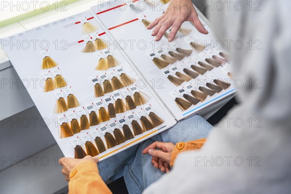 Client and hairdresser comparing color chart swatches in salon, discussing shades and tones to