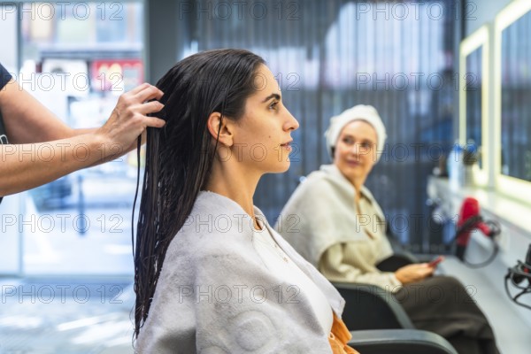 Hairdresser applying hair treatment to a young woman's wet, dark hair, highlighting beauty, care,