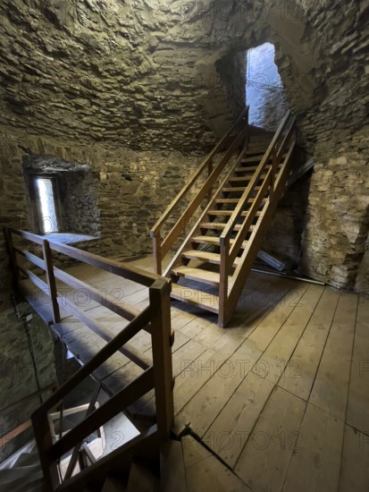 Modern wooden staircase for visitors tourists in keep made of quarry stone masonry Castle tower of