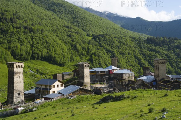 A mountain village with historic towers surrounded by green forests and mountains, defensive