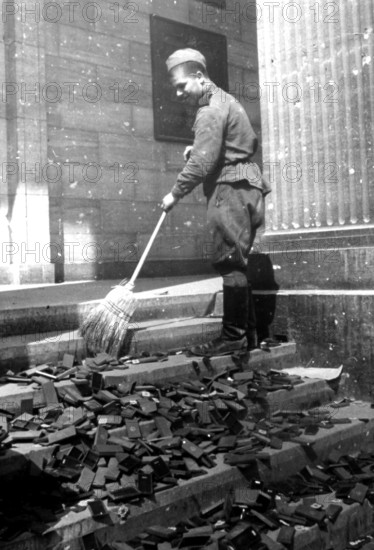 Soldier sweeping boxes of National Socialist medals from a staircase in the Reich Chancellery,
