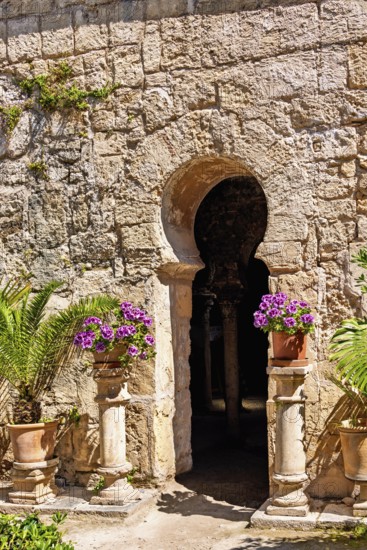 Old Moorish building with a vault and beautiful flowers in terracotta pots in the sunshine at the