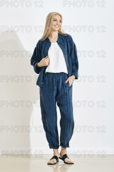 Smiling woman stands in a studio wearing a comfortable outfit, consisting of a matching jacket and