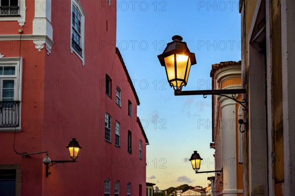 Facades of old houses illuminated by lanterns during sunset on the streets of Pelourinho in