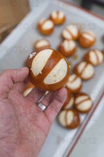 Simple pretzel held in hand with salt, more in the background, baking rolls, Haselstaller Hof,