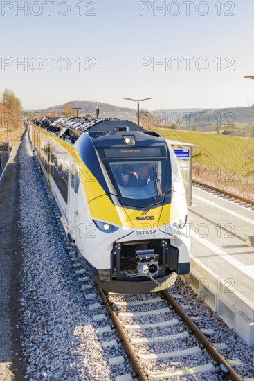 Front view of a modern train at the station, surrounded by hilly landscape, test run on the new