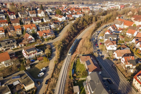 Aerial view of a city with red roofs and a train on rails, test run on the new Hermann-Hesse