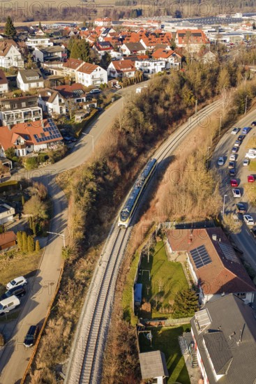 Aerial view of a railway line running through a town with red roofs and surrounding nature, test