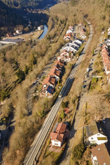 Aerial view of a village with railroad tracks, surrounded by forests and a river, test run on the