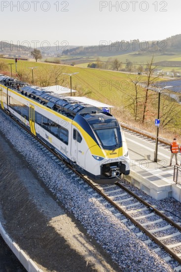 Modern train on the platform in a landscape surrounded by fields under clear skies, test run on the