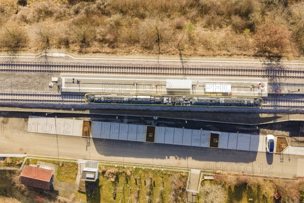 Aerial view of a train station with train tracks surrounded by trees and vegetation, test run on