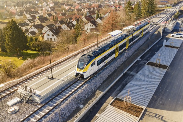 Train at a small train station surrounded by village houses and green countryside, test trip on the