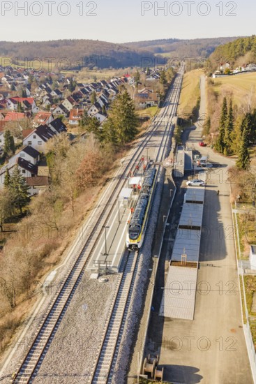 Zug travels on a railway line through a rural, densely built-up area with trees, test run on the