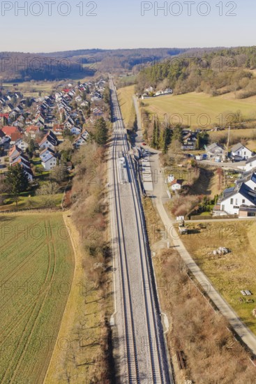 Aerial view of railroad tracks running through a rural area with houses and fields, test run on the