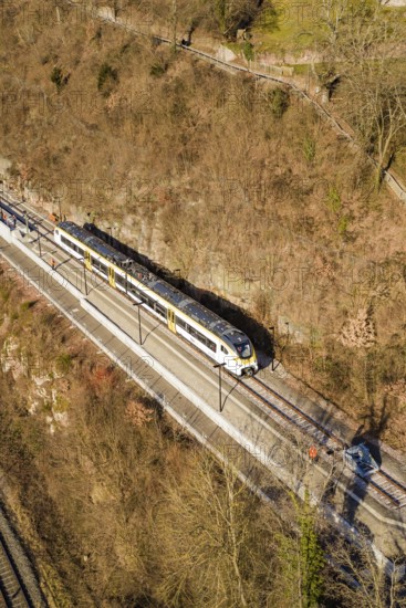 Aerial view of a train traveling through a wooded area surrounded by bare trees, test run on the