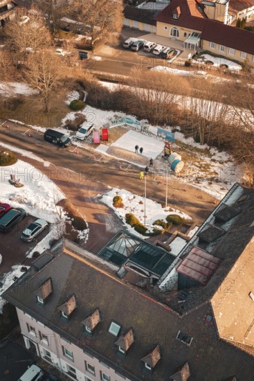 Bird's eye view of a snowy road with buildings and parked cars on a sunny winter day, Freudenstadt,