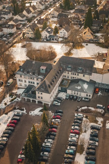 A large building with an adjacent parking lot and a few snow-covered cars, district office,