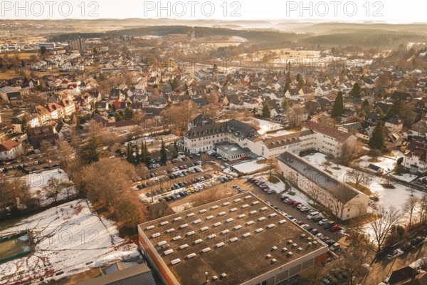 Panoramic view of a snowy city with buildings and trees from a bird's eye view in warm light,