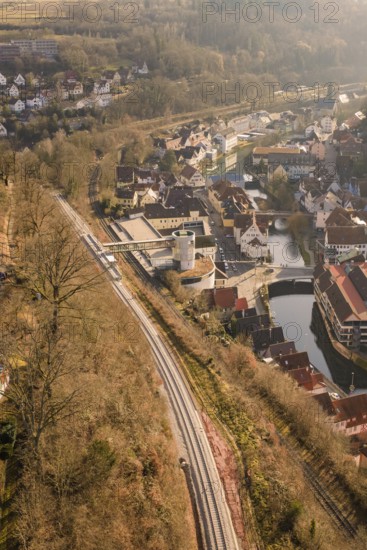 City view from the air with railway line along a wooded slope and river, test run on the new