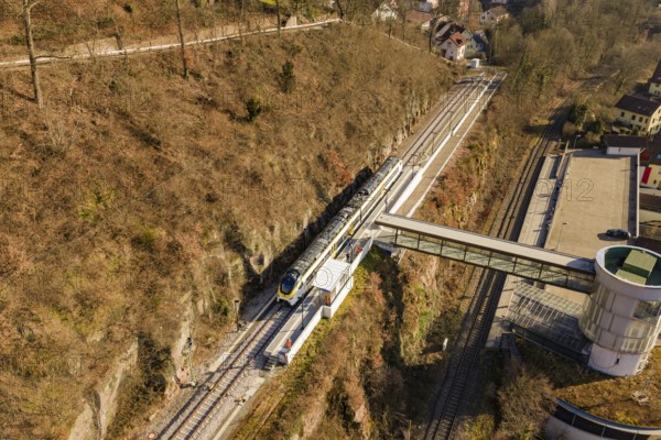 Aerial view of a train station with a train in hilly landscape and autumn colors, test run on the