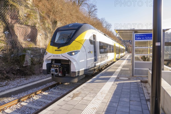 Modern train at a small train station surrounded by trees and hills, test run on the new
