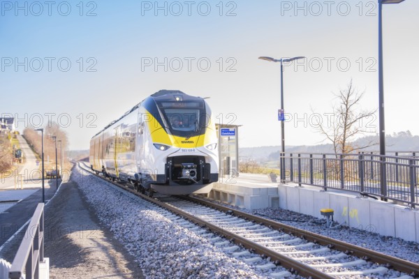 Modern train on the track in front of a small train station in sunshine, test run on the new