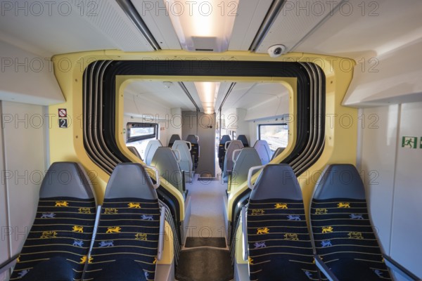 Train compartment with yellow accents and grey seats in bright surroundings, test run on the new