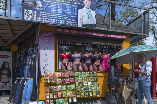 Sales stand with mannequins with corsetry, in front of a stand with bags of vegetable seeds,